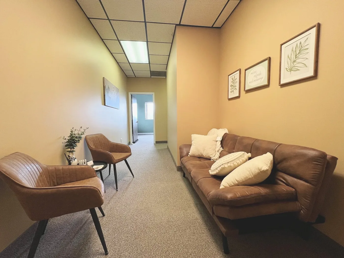 The waiting area outside suite 325 with a sofa, two chairs and botanical prints